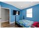 Bright bedroom with blue walls featuring a large TV and natural light at 3015 S Rybolt Ave, Indianapolis, IN 46241
