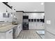 Bright kitchen featuring white cabinets, granite countertops, and stainless steel appliances on herringbone-patterned wood floors at 3015 S Rybolt Ave, Indianapolis, IN 46241
