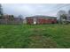 Backyard featuring a brick house with a white back door, small patio area, and partially fenced grassy area at 314 S Taft Ave, Indianapolis, IN 46241