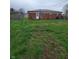 View of a backyard featuring a brick house with a back door and a grassy yard with a fence at 314 S Taft Ave, Indianapolis, IN 46241
