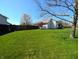 Spacious fenced backyard with lush green grass and mature trees provides privacy and a park-like setting at 3730 Cheyenne Ct, Columbus, IN 47203