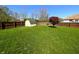Large, green backyard features a storage shed and mature tree, surrounded by a wooden privacy fence at 3730 Cheyenne Ct, Columbus, IN 47203