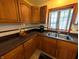 Traditional kitchen featuring wood cabinets, dark countertops, and a double basin sink below a window at 3730 Cheyenne Ct, Columbus, IN 47203