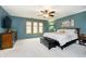 This bedroom features blue walls, carpet floors, a ceiling fan, and a large window at 3892 Arrowhead Ct, Greenfield, IN 46140