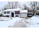 View of house with snow-covered yard and driveway with vehicle under carport at 4107 Eisenhower Dr, Indianapolis, IN 46254