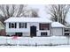 Winter view of the quaint home with a picket fence and snow-covered yard at 4107 Eisenhower Dr, Indianapolis, IN 46254
