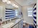 Bathroom features a double vanity, a large mirror, and a shower with a blue and white striped curtain at 4140 Omaha Dr, Bargersville, IN 46106