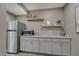 Cozy kitchenette with grey cabinets, granite countertops, stainless steel appliances, and decorative floating shelves at 4140 Omaha Dr, Bargersville, IN 46106