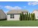 Well-maintained backyard featuring lush green grass and privacy trees, complemented by a charming home exterior at 5069 Lilium Dr, Plainfield, IN 46168