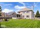 View of the two-story home featuring a lush lawn, wood fence, screened-in porch, and mature trees on a beautiful day at 5343 Ripplingbrook Way, Carmel, IN 46033