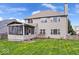 View of the two-story home featuring a lush lawn, wood fence, screened-in porch, and mature trees on a beautiful day at 5343 Ripplingbrook Way, Carmel, IN 46033