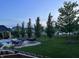 Well-maintained backyard featuring a manicured lawn, mature trees, and an inviting outdoor patio with lounge chairs and tables at 5373 Ashby Ct, Greenwood, IN 46143