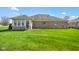 Backyard view of a brick home featuring a well-maintained lawn and a bright sunroom addition at 5766 Kensington S Way, Plainfield, IN 46168