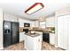 Well-equipped kitchen features an island, black appliances, white cabinetry and stone tile flooring at 5856 Long Ridge Pl, Indianapolis, IN 46221