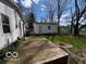 View of backyard with a wooden deck, detached garage, green grass, and mature trees at 5868 Hillside Ave, Indianapolis, IN 46220