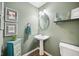 Stylish half bathroom with pedestal sink, decorative mirror, and painted green walls at 6526 Angel Falls Dr, Noblesville, IN 46062