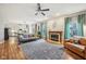 Bright living room featuring hardwood floors, a ceiling fan, a fireplace, and an open floor plan to the kitchen at 6526 Angel Falls Dr, Noblesville, IN 46062