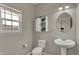 Well-lit half bathroom featuring a pedestal sink, round mirror, and window at 6674 Buhrstone Ln, Avon, IN 46123