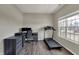 A home office featuring a desk setup, a dark color scheme, wood floors, and a treadmill near a bright window at 6674 Buhrstone Ln, Avon, IN 46123
