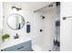 Stylish bathroom featuring modern vanity, round mirror, and tiled shower with dark fixtures at 7624 Snowflake Dr, Indianapolis, IN 46227