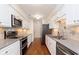 Galley kitchen features stainless appliances, a tile backsplash, and white cabinetry at 8535 Olde Mill Circle West Dr, Indianapolis, IN 46260