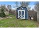 Backyard blue storage shed with white trim and a nearby garden at 8747 Knotty Pine Ct, Indianapolis, IN 46227