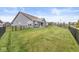 Wide view of a spacious backyard bordered by a black metal fence and mature landscaping, side angle at 9925 Glendon Ct, McCordsville, IN 46055