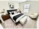 Stylish bedroom featuring a black headboard, neutral bedding, modern decor, a window, and a comfortable seating area at 10200 Cheswick Ln, Fishers, IN 46037