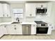 A kitchen features white cabinets, quartz countertops, and stainless steel appliances at 10200 Cheswick Ln, Fishers, IN 46037