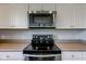 Kitchen featuring stainless steel range, microwave, white cabinets, and gray countertops at 10602 Pintail Ln, Indianapolis, IN 46239