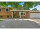 A wide concrete driveway leads up to the front porch of this tan brick and brown sided single story home at 11054 N Shelby 490 W, New Palestine, IN 46163