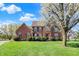 Beautiful two-story brick home with a well-manicured lawn and attractive landscaping and blossoming tree at 11599 Braemar Ct, Carmel, IN 46032