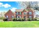 Charming two-story brick home with lush green lawn, manicured bushes, and blossoming tree at 11599 Braemar Ct, Carmel, IN 46032