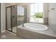 An elegant bathroom has a large soaking tub, glass shower, and serene views from a large window at 13316 E Lieder Way, Fishers, IN 46037