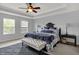 Spacious bedroom featuring tray ceilings, a ceiling fan, two large windows, and a comfortable bed with bench at 13510 E 131St St, Fishers, IN 46037