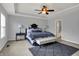 Spacious bedroom featuring tray ceilings, a ceiling fan, two large windows, and a comfortable bed with bench at 13510 E 131St St, Fishers, IN 46037