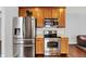 Modern kitchen appliances including stainless steel fridge, oven, and microwave set against warm wood cabinets and floors at 13510 E 131St St, Fishers, IN 46037