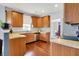 Well-lit kitchen with oak cabinets, wood floors, stainless steel appliances, and a view into the dining room at 13510 E 131St St, Fishers, IN 46037