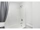 A bright bathroom featuring a white tiled shower, modern fixtures, and a gray shower curtain at 15379 Alperton Rd, Fishers, IN 46037