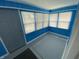 Bright sunroom with blue wood paneled walls, gray floor, and plenty of natural light from the windows at 1546 Kappes St, Indianapolis, IN 46221