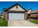 Charming home featuring a two-car garage, brick accents, complemented by lush green lawn and blue skies at 1720 Justin Ct, Indianapolis, IN 46219