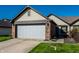 Charming home featuring a two-car garage, brick accents, complemented by lush green lawn and blue skies at 1720 Justin Ct, Indianapolis, IN 46219