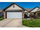 Charming home featuring a two-car garage, brick accents, complemented by lush green lawn and blue skies at 1720 Justin Ct, Indianapolis, IN 46219