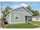 Exterior view of charming home featuring green siding, grey shingle, covered porch and well-maintained lawn at 217 W 35Th St, Indianapolis, IN 46208