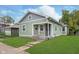 Exterior view of a home featuring green siding, grey shingle, covered porch, and manicured lawn at 217 W 35Th St, Indianapolis, IN 46208