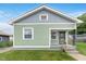 Charming home exterior with green siding, grey shingle, covered porch and well-maintained front lawn at 217 W 35Th St, Indianapolis, IN 46208