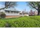 View of a single-story home from the yard showcasing brick accents and lush landscaping at 318 Camby St, Greenwood, IN 46142