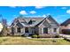 Charming stone and siding home with a well-manicured lawn and a lovely walkway leading to the front door at 3582 Pete Dye Blvd, Carmel, IN 46033