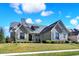 Attractive home featuring a stone and siding facade, set on a well-kept lawn under a bright, cloudy sky at 3582 Pete Dye Blvd, Carmel, IN 46033