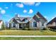 Beautifully landscaped home with stone and siding, complemented by a lush green lawn and blue skies at 3582 Pete Dye Blvd, Carmel, IN 46033